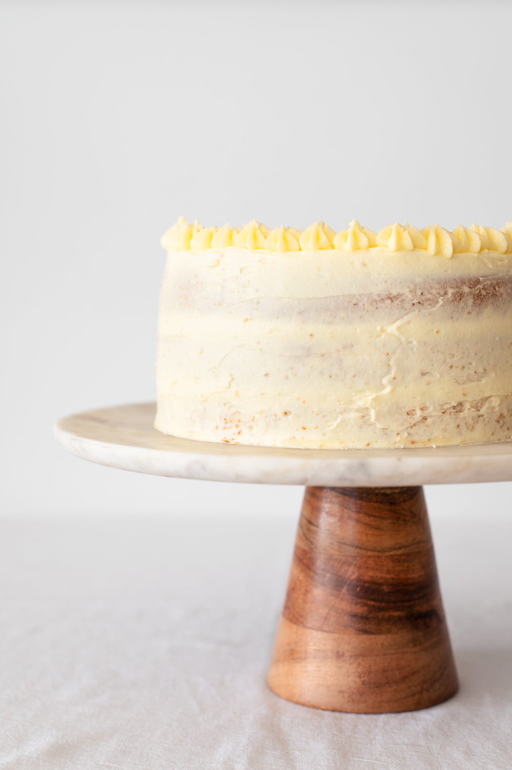 A three layer vanilla cake with vanilla buttercream on a cake stand