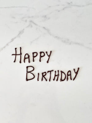 "Happy Birthday" message piped in dark chocolate 