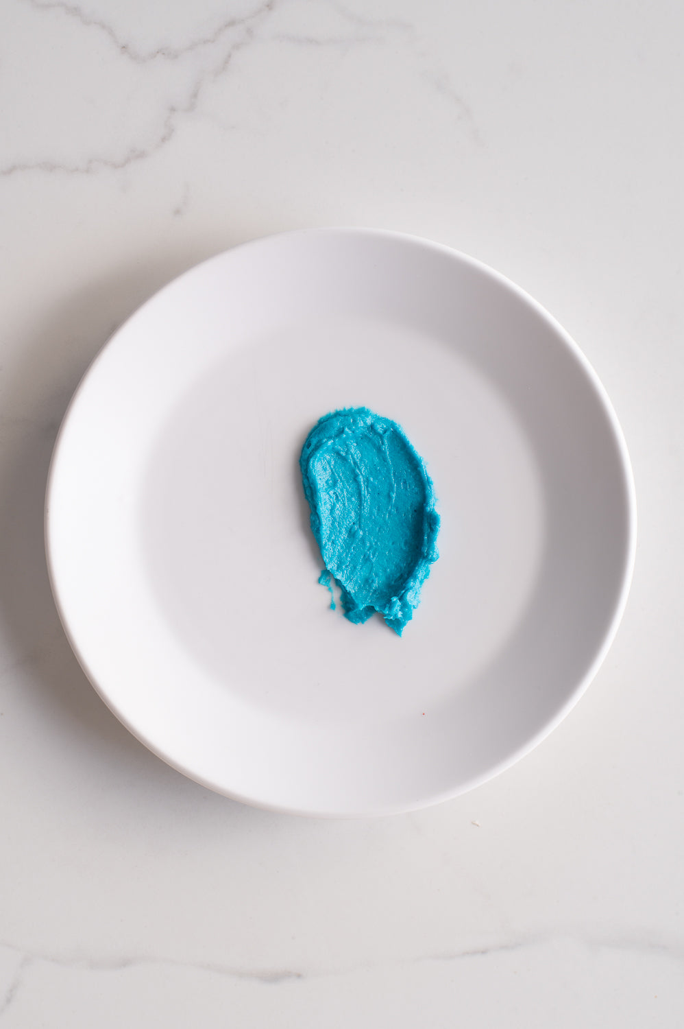 An organic shape of blue buttercream icing on a plate