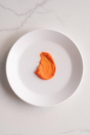 An organic shape of orange buttercream icing on a plate