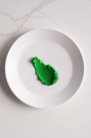 An organic shape of green buttercream icing on a plate