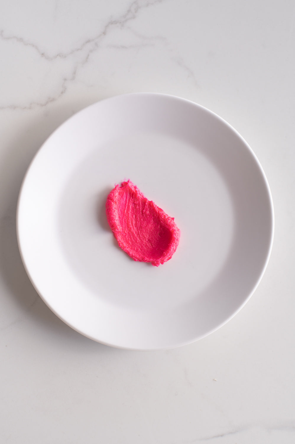 An organic shape of pink buttercream icing on a plate