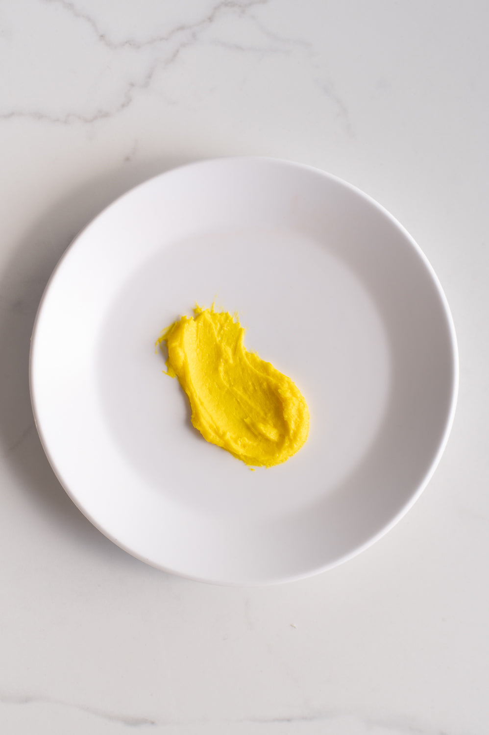 An organic shape of yellow buttercream icing on a plate