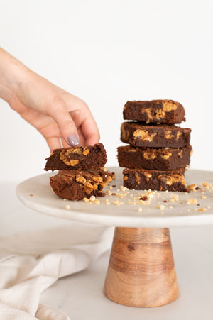 A stack of peanut butter and chocolate brownies on a cake stand