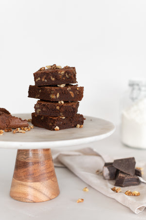 A stack of chocolate and walnut brownies displayed on a cake stand