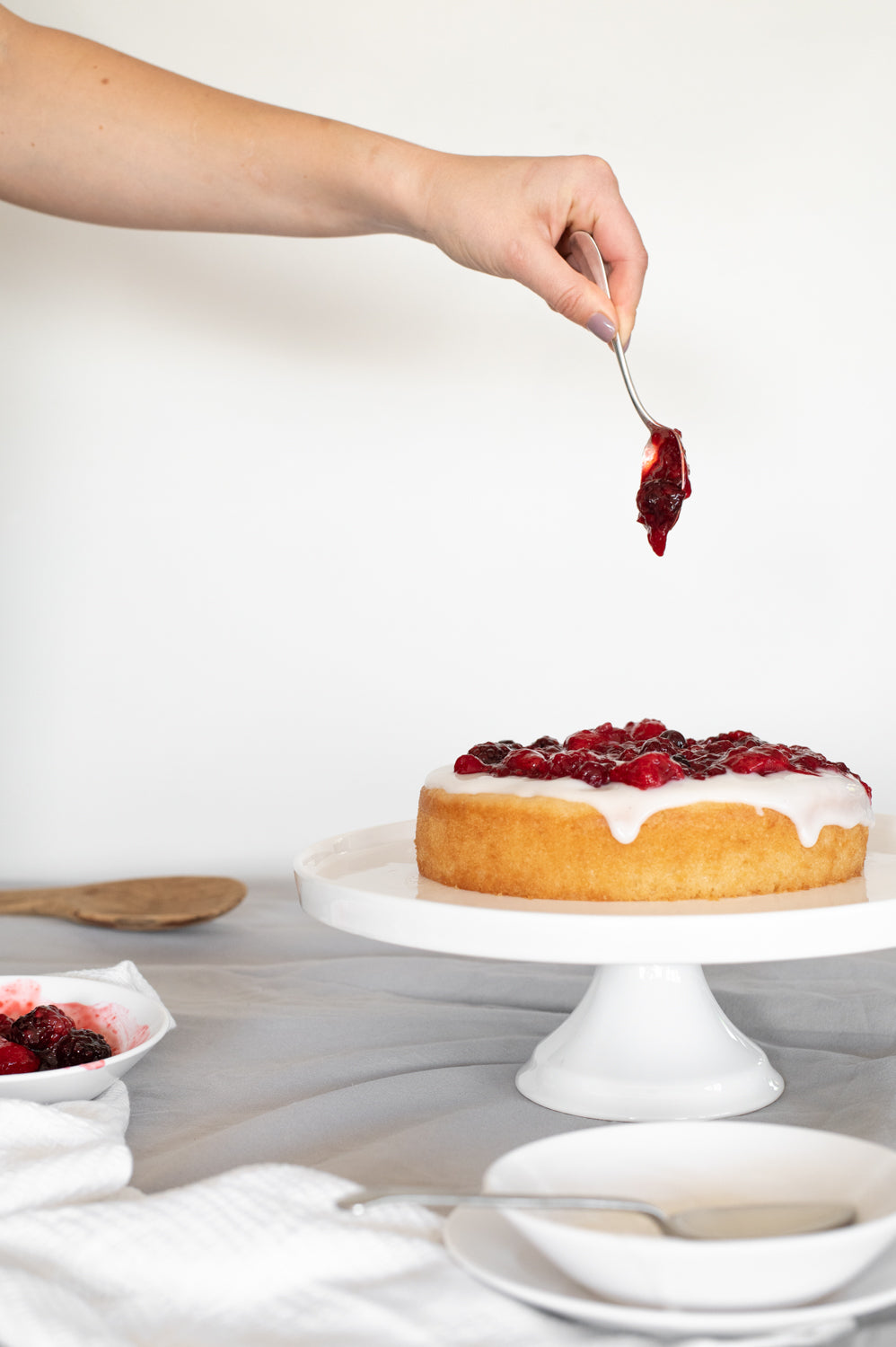 Lemon cake topped with coconut yoghurt icing and berry coulis 