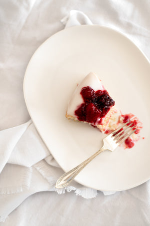 A slice of lemon cake topped with coconut yoghurt icing and berry coulis 