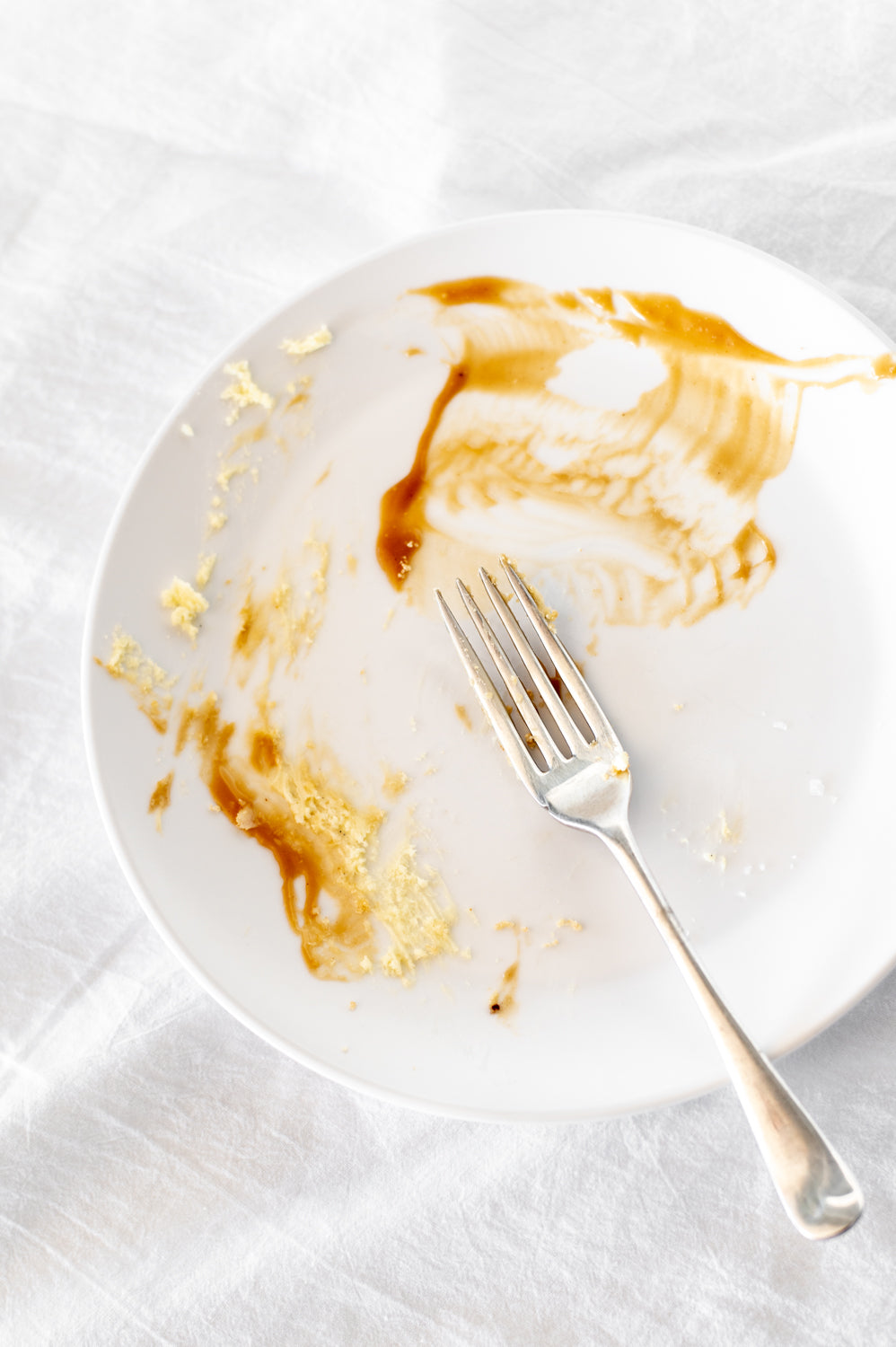 An empty plate with a fork and caramel scrapings