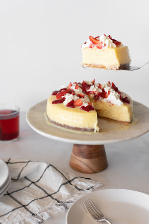 A slice of Strawberries and Cream Baked Cheesecake on a cake stand