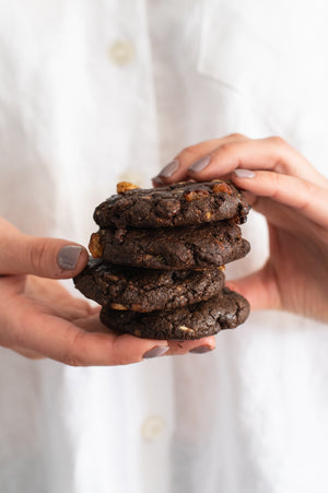 Hands holding a stack of chewy triple choc chip cookies