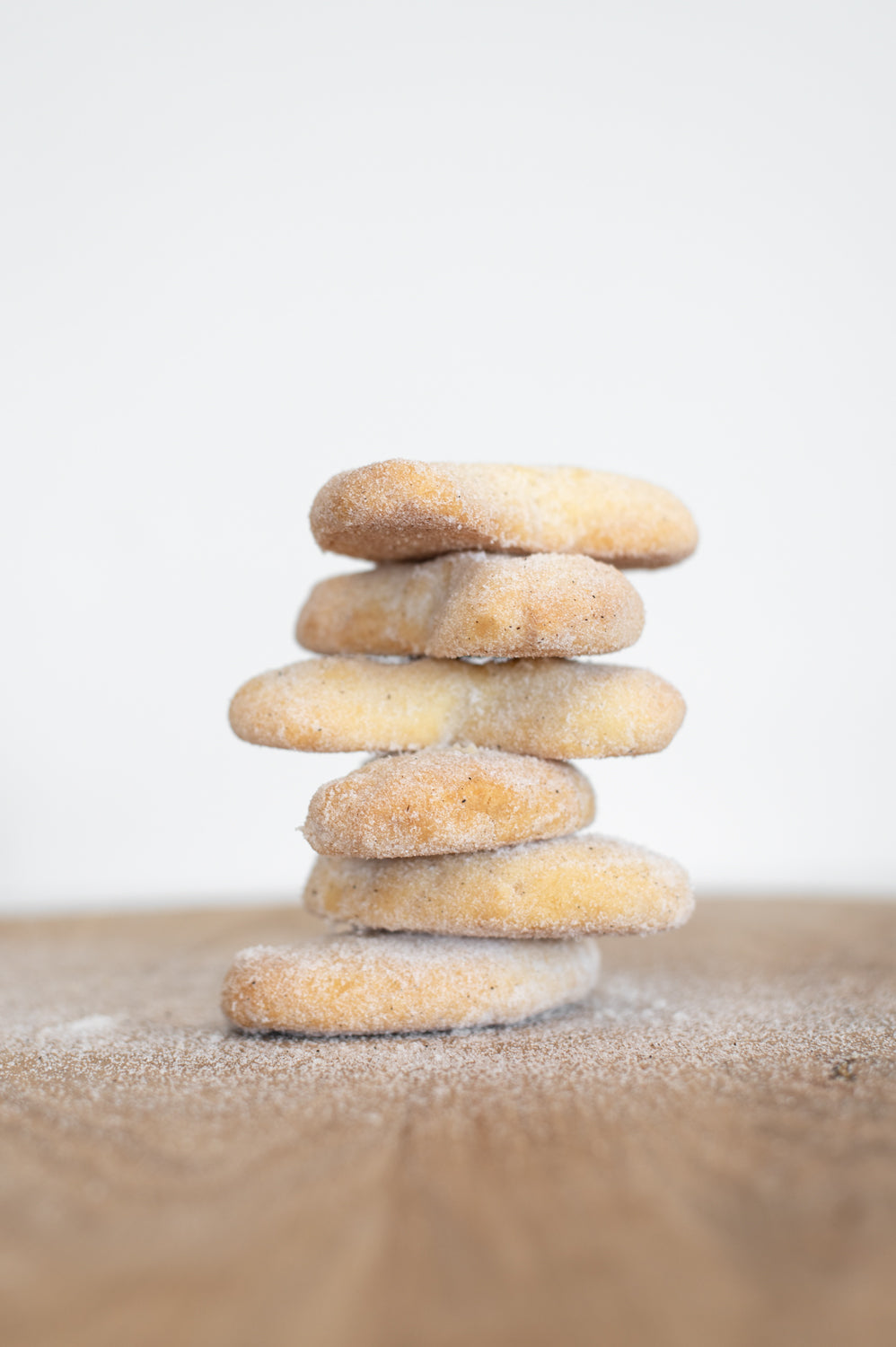 A stack of crescent shaped cookies covered in sugar