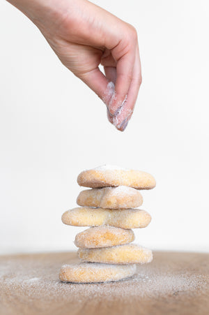 A stack of crescent shaped cookies covered in sugar