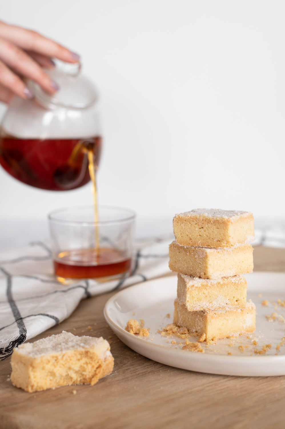 A stack of shortbread biscuits next to a pot of tea