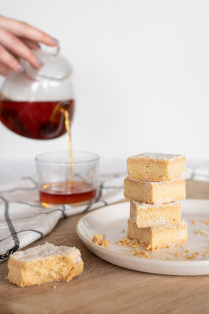 A stack of shortbread biscuits next to a pot of tea