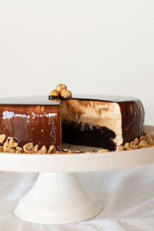 A Chocolate Hazelnut Mousse Cake on a cake stand with a sliced removed to show the inside