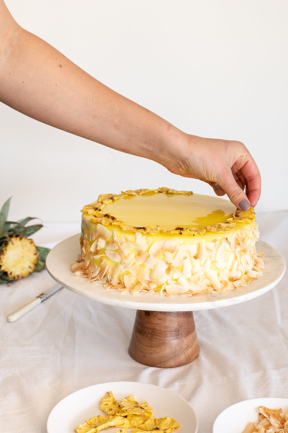 A yellow tropical cake garnished with pineapple and coconut