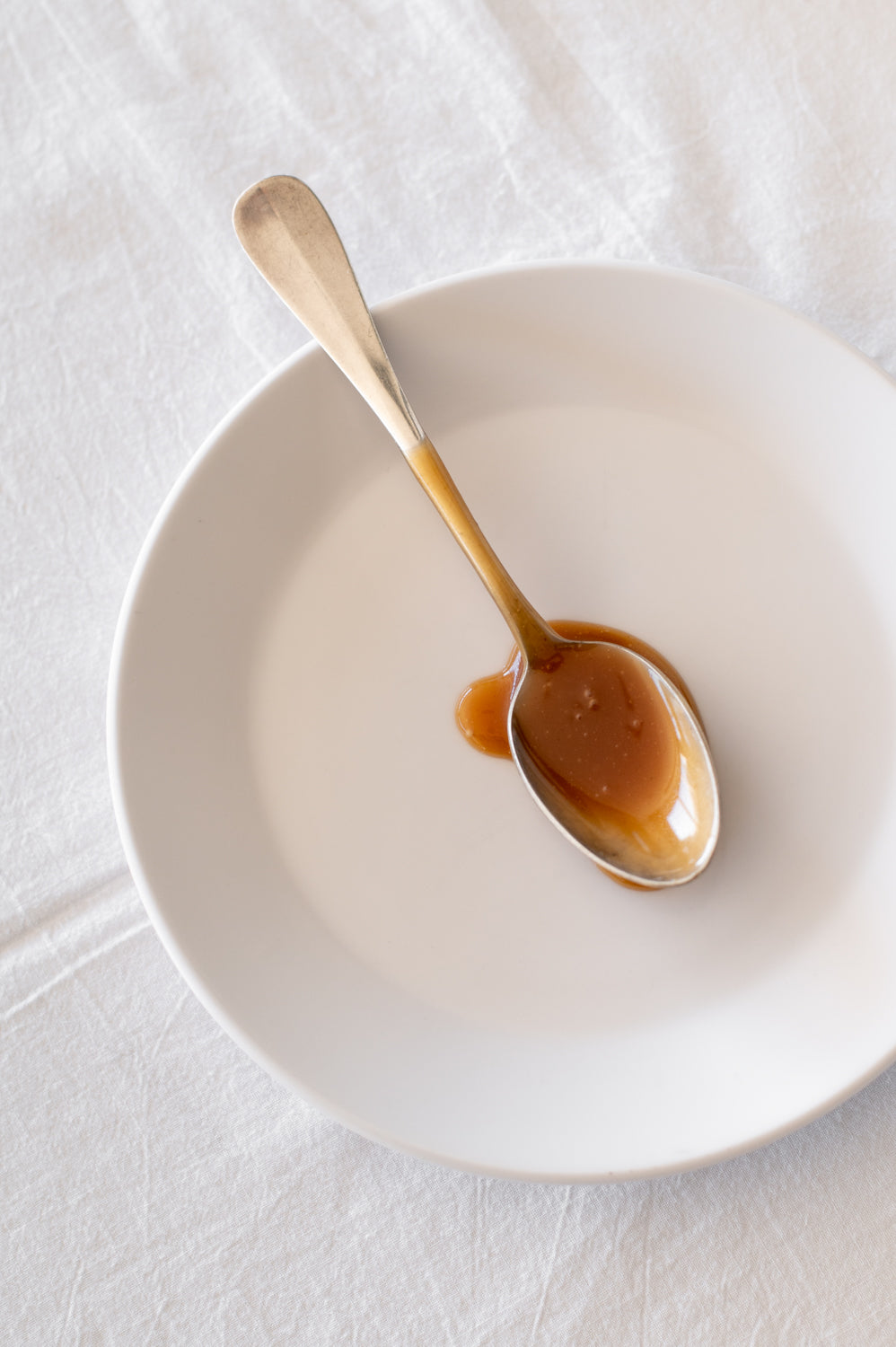 A teaspoon covered with salted butter caramel, resting on a plate 